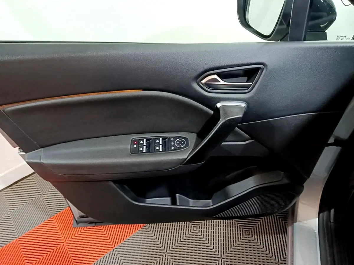 Vue intérieure côté gauche de la porte avant grise du Renault Captur Intens E-Tech avec commandes de vitres et rétroviseur.