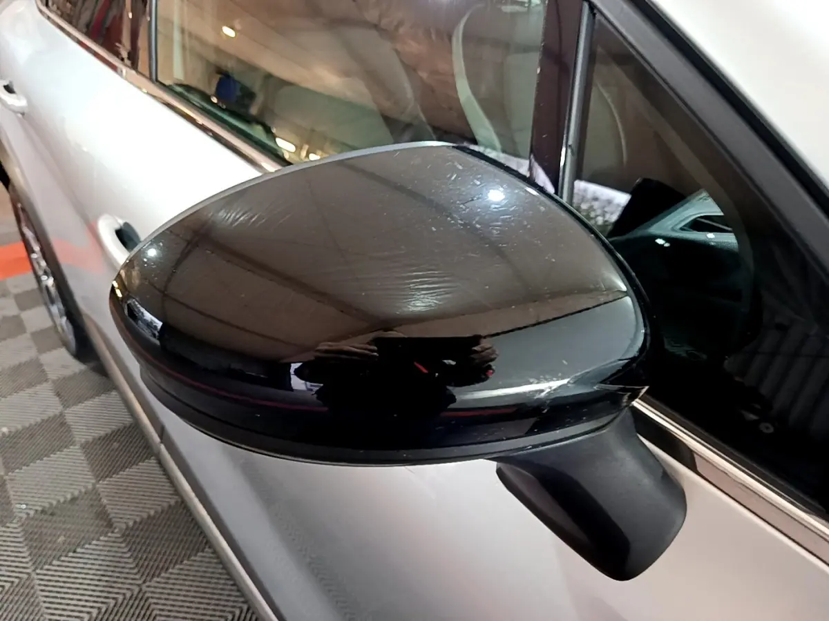 Rétroviseur noir en gros plan côté gauche d’un Renault Captur gris clair hybride rechargeable vu de profil.