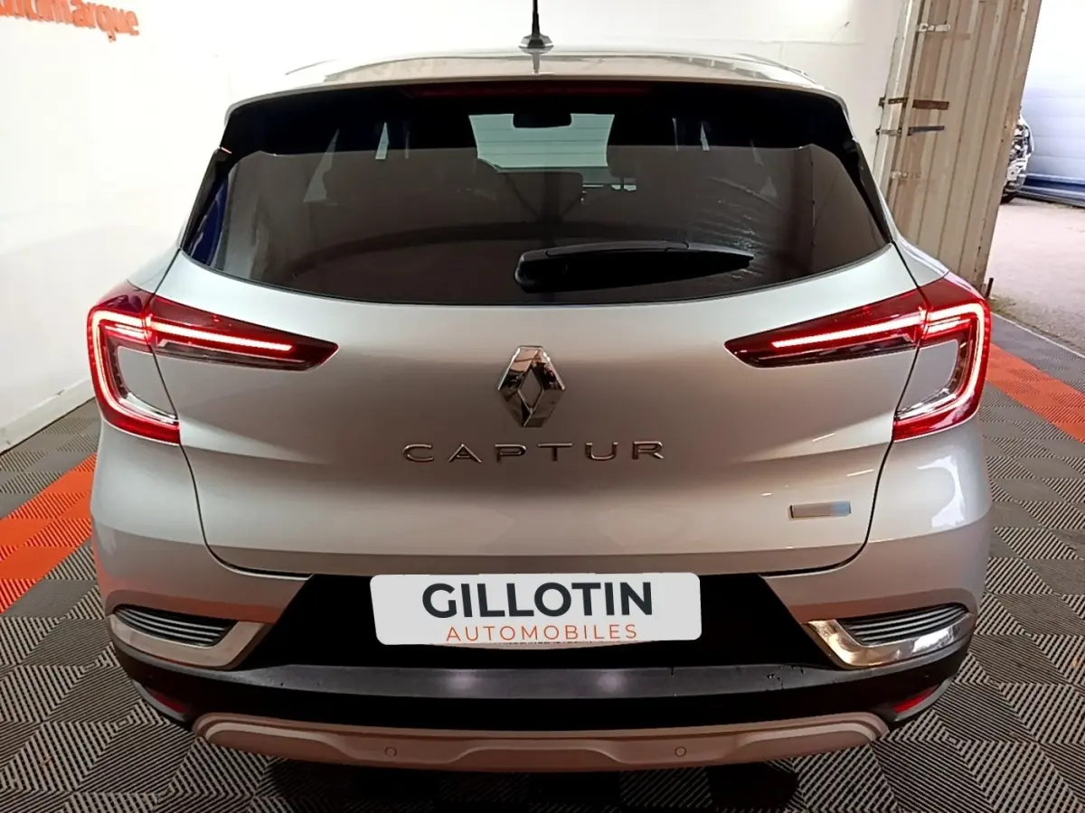 Vue arrière d’un Renault Captur gris clair avec feux LED allumés dans un garage.
