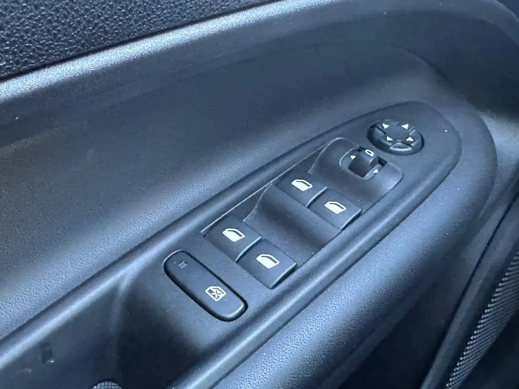 Gros plan sur les commandes électriques des vitres et rétroviseurs côté conducteur du Jeep Avenger gris 2025.