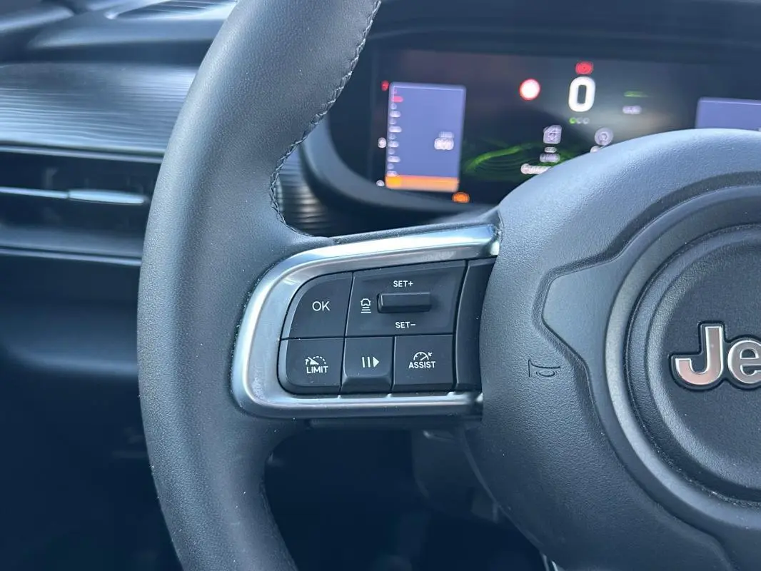 Gros plan sur le volant noir du Jeep Avenger 2025 avec commandes de régulateur et affichage numérique en arrière-plan.