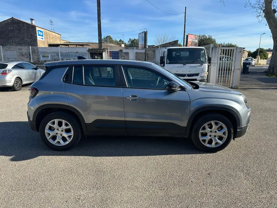 Vue de profil côté gauche d'un Jeep Avenger gris 2025 avec jantes alliage 17 pouces sur un parking extérieur.
