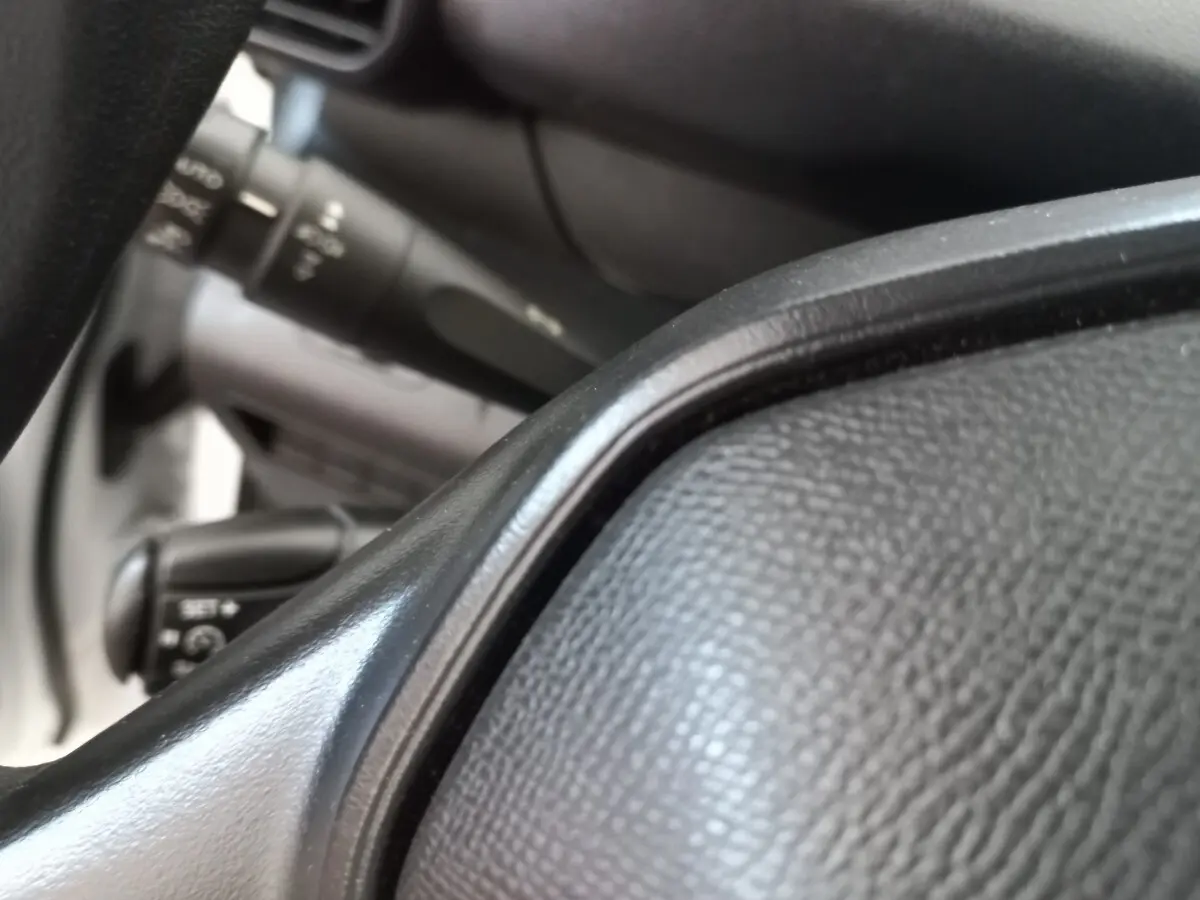 Gros plan sur le volant noir et les commandes derrière sur un Peugeot Partner blanc, vue intérieure côté conducteur.