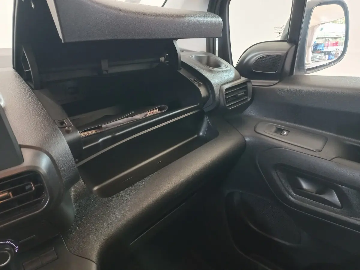 Intérieur côté passager du Peugeot Partner 2021, boîte à gants ouverte et tableau de bord noir.