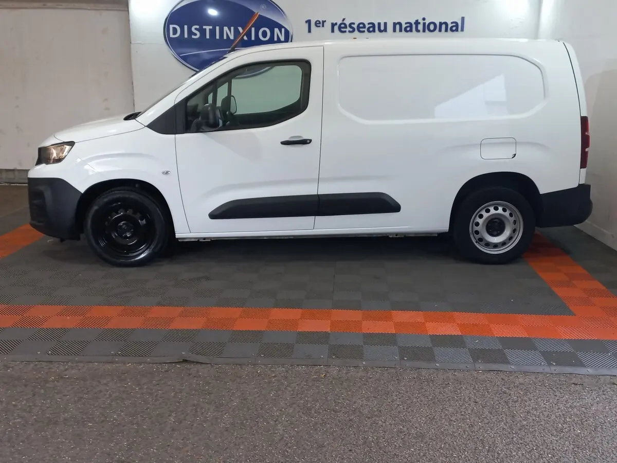 Vue de profil côté gauche d'un utilitaire Peugeot Partner blanc avec protections latérales noires et jantes acier.