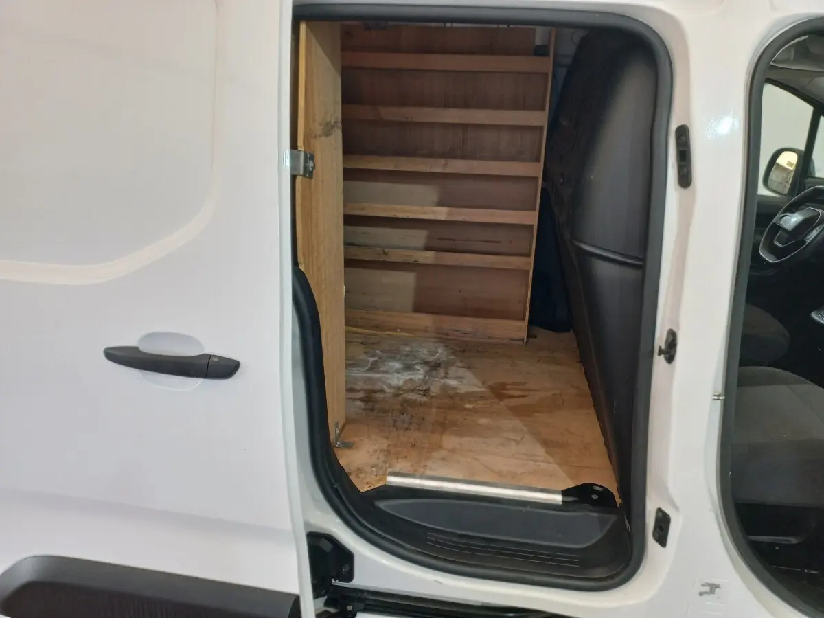 Vue latérale gauche du Peugeot Partner blanc 2021 avec porte coulissante ouverte montrant l’intérieur utilitaire en bois.
