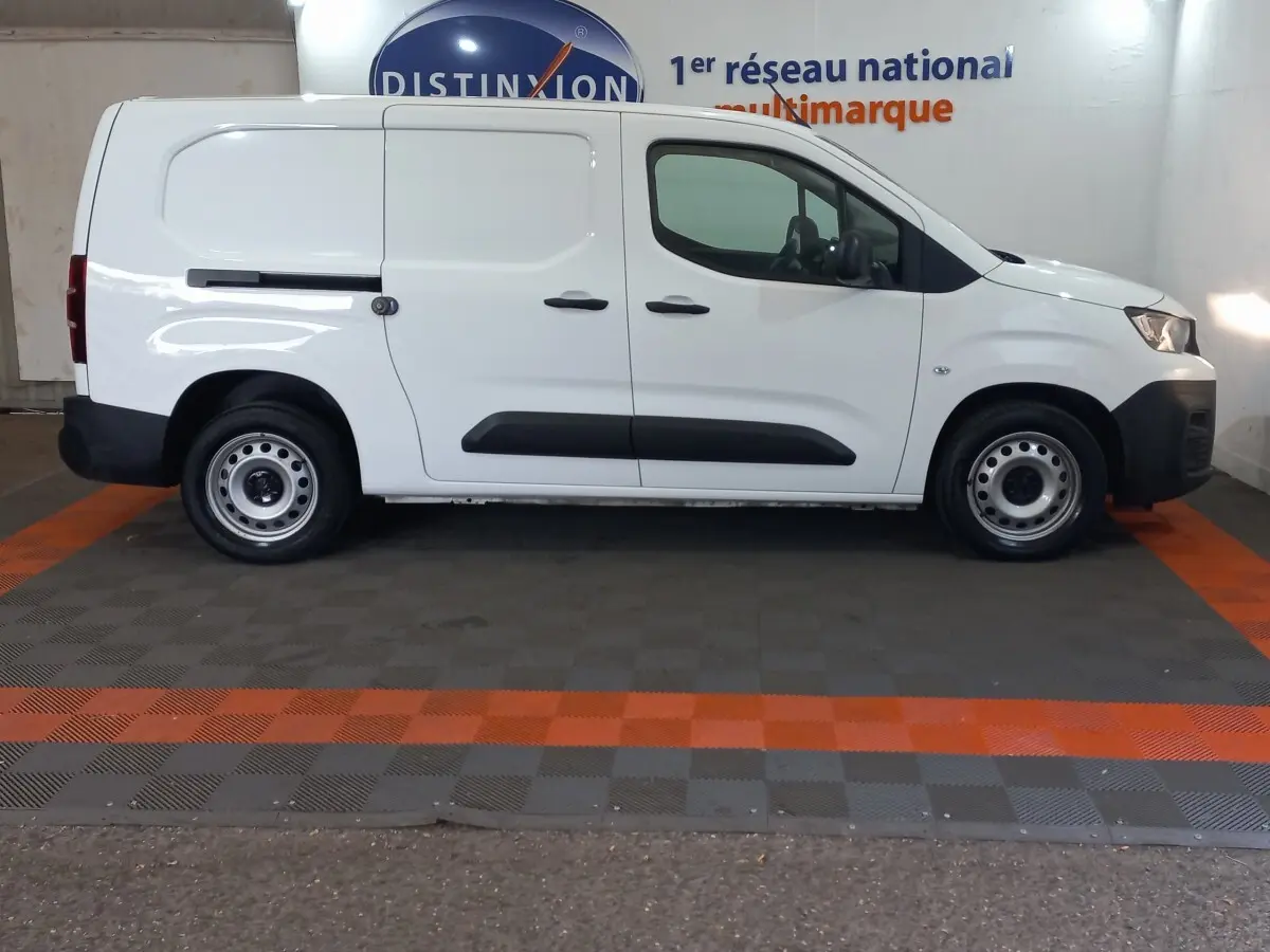 Vue latérale droite d’un utilitaire Peugeot Partner blanc, version BlueHDi 100 Premium, avec portes coulissantes et jantes acier.