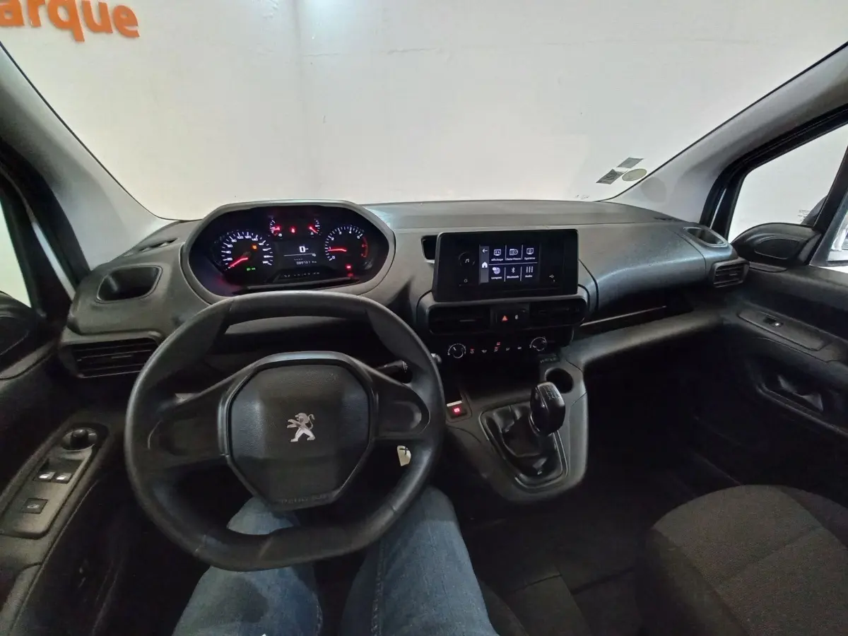 Vue intérieure du poste de conduite du Peugeot Partner blanc, avec volant, tableau de bord numérique et écran central tactile.