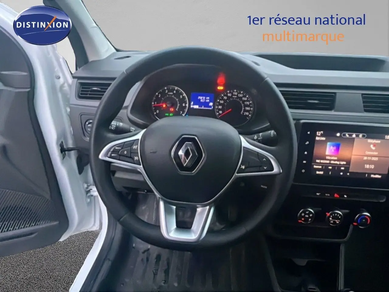 Vue intérieure centrée sur le volant Renault d'un Express Van blanc glacier 2023 avec tableau de bord et écran tactile.