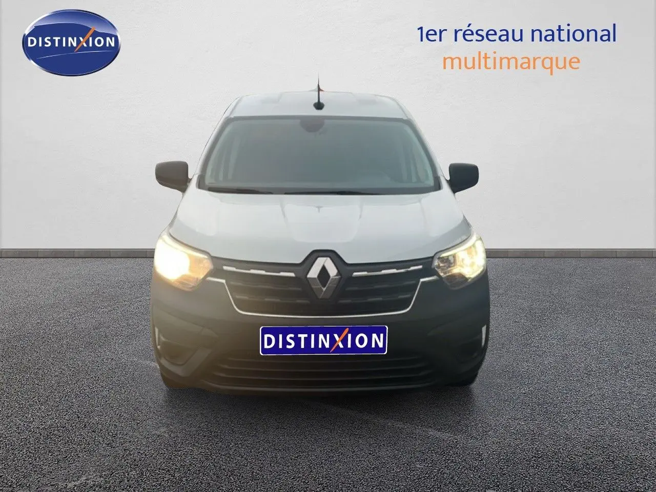 Vue frontale d'un Renault Express Van blanc glacier avec phares allumés sur fond neutre.