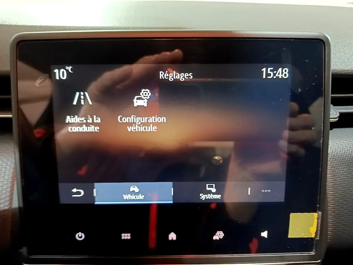 Écran tactile central de la Renault Clio gris clair 2023 affichant les réglages d’aides à la conduite et configuration véhicule.