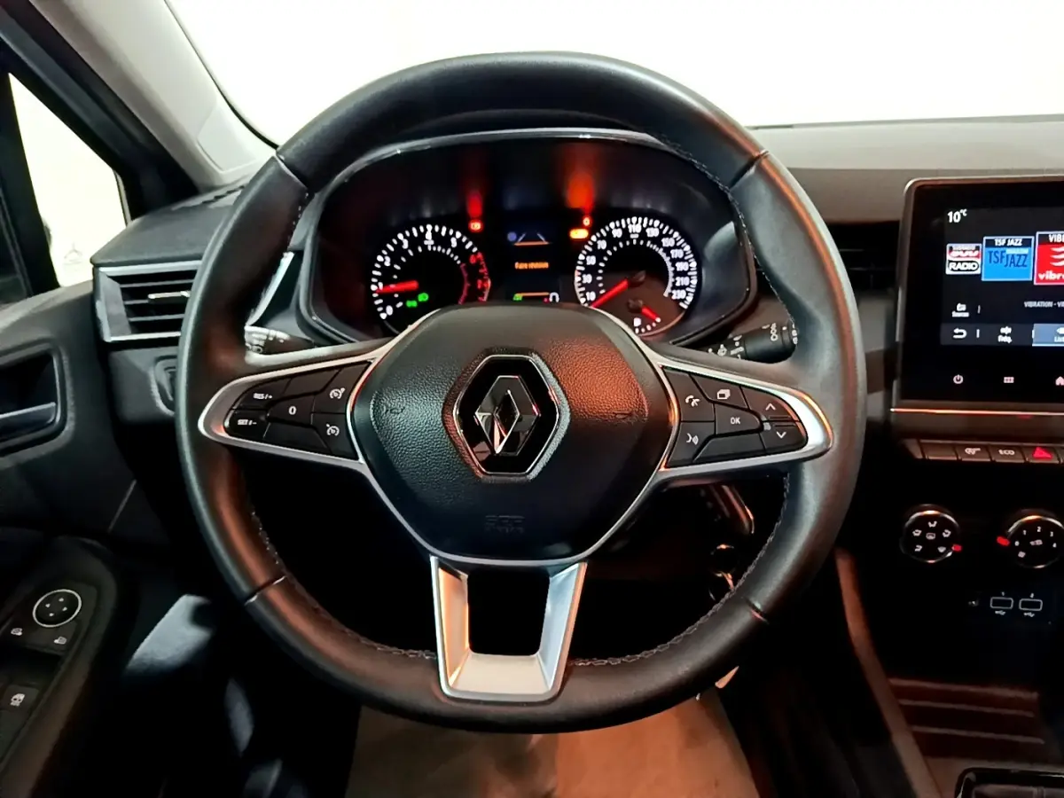 Vue intérieure centrée sur le volant cuir noir de la Renault Clio 2023 avec tableau de bord et écran tactile visible à droite.