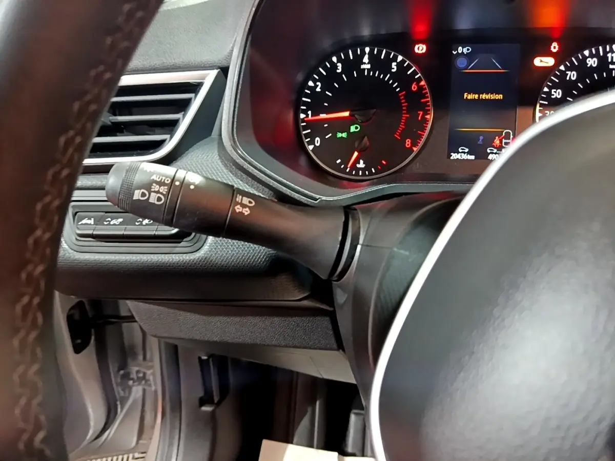 Gros plan sur le combiné d'instruments et le volant cuir noir de la Renault Clio gris clair, affichage digital allumé.