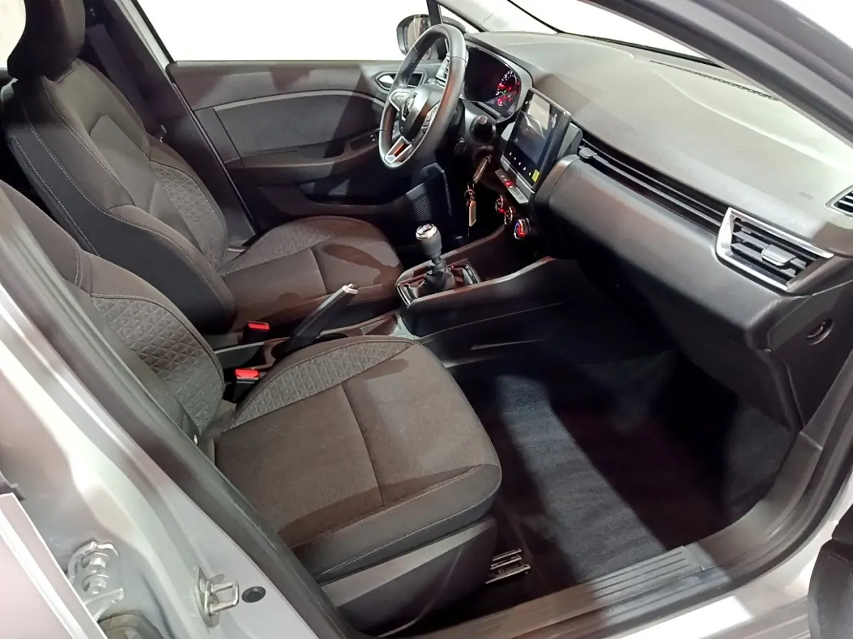 Vue intérieure côté conducteur de la Renault Clio gris clair 2023, avec tableau de bord moderne et boîte manuelle.