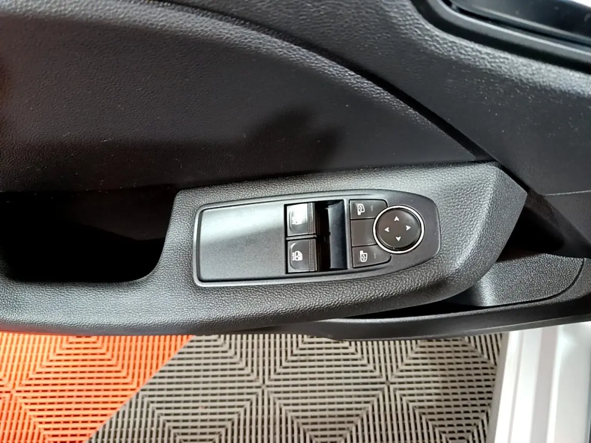 Gros plan sur la commande des vitres et rétroviseurs côté gauche d'une Renault Clio gris clair 2023.