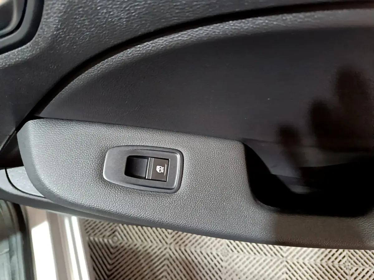 Gros plan sur le bouton de verrouillage des portes côté conducteur de la Renault Clio Equilibre TCe 90 gris clair 2023.