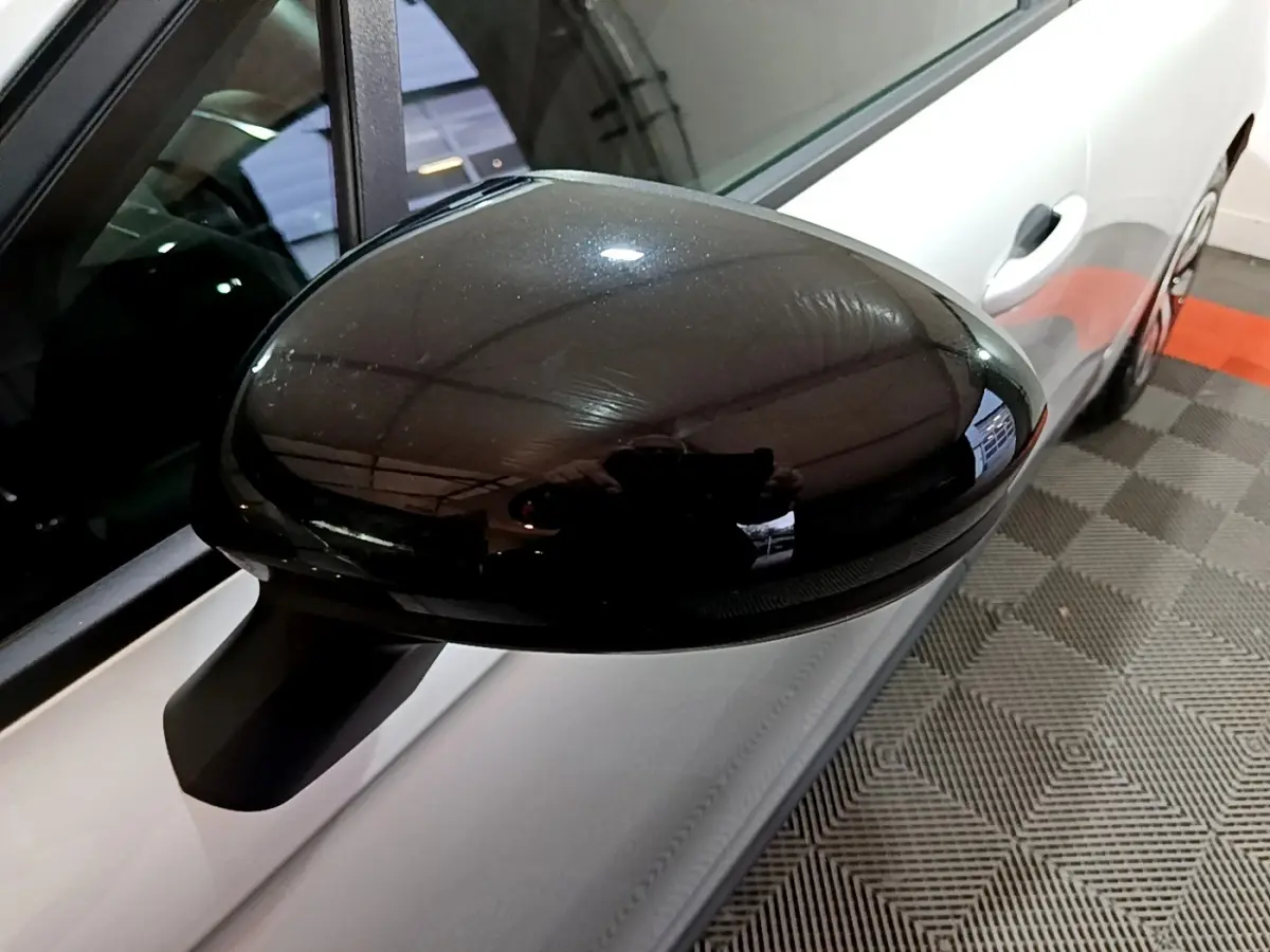 Gros plan sur le rétroviseur noir côté gauche d’une Renault Clio gris clair vue de profil.