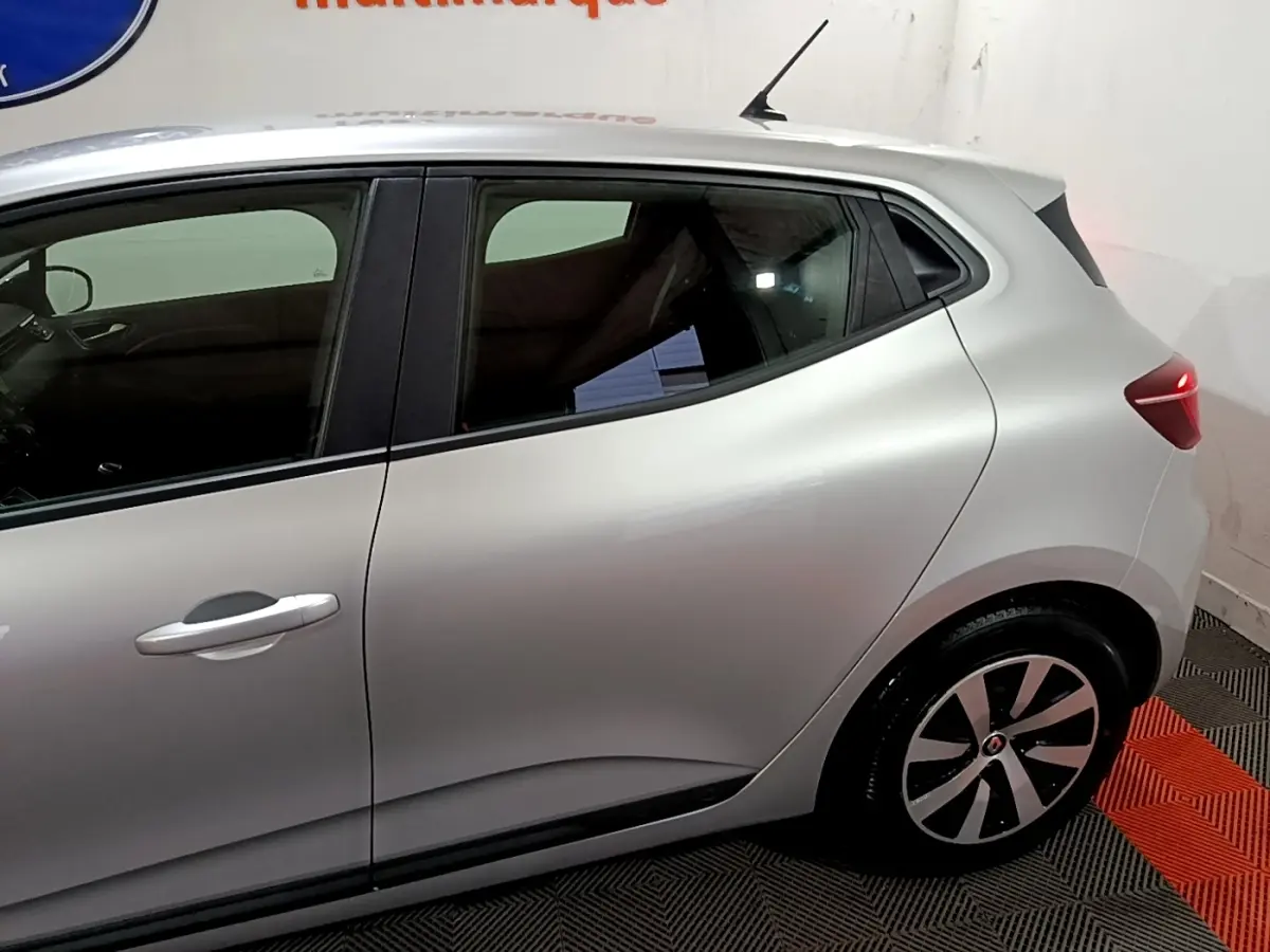 Vue latérale droite d'une Renault Clio 2023 gris clair, mettant en valeur la ligne fluide et les jantes stylisées.