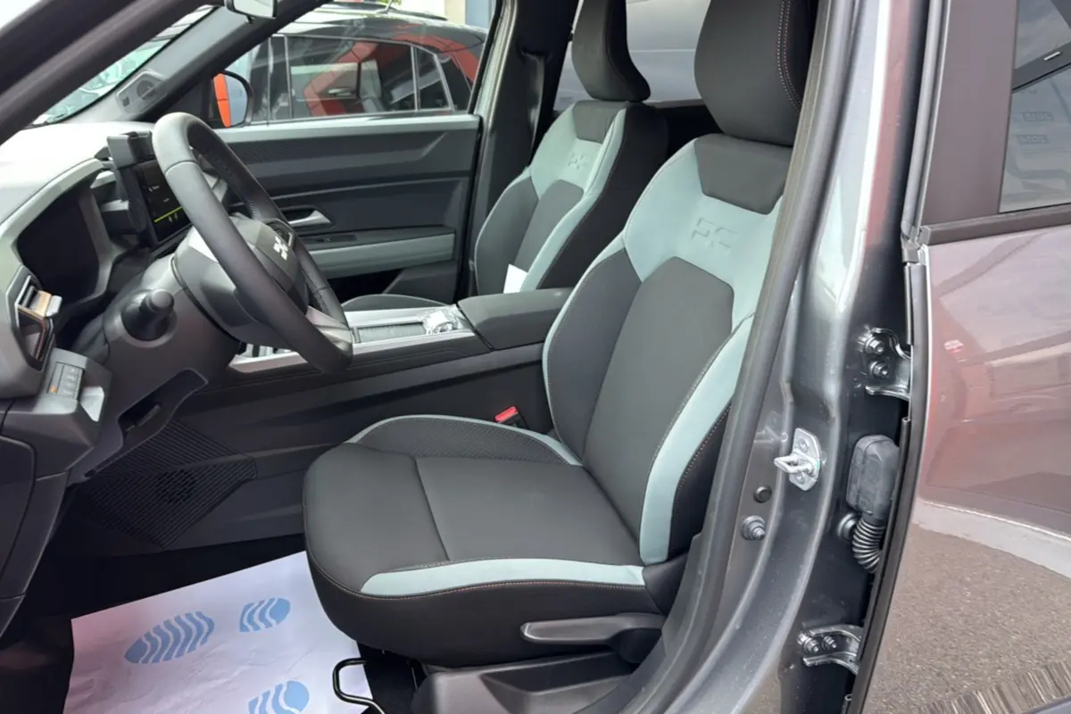 Vue intérieure côté conducteur du Dacia Bigster gris schiste, sièges bi-ton avec logo embossé et volant cuir.