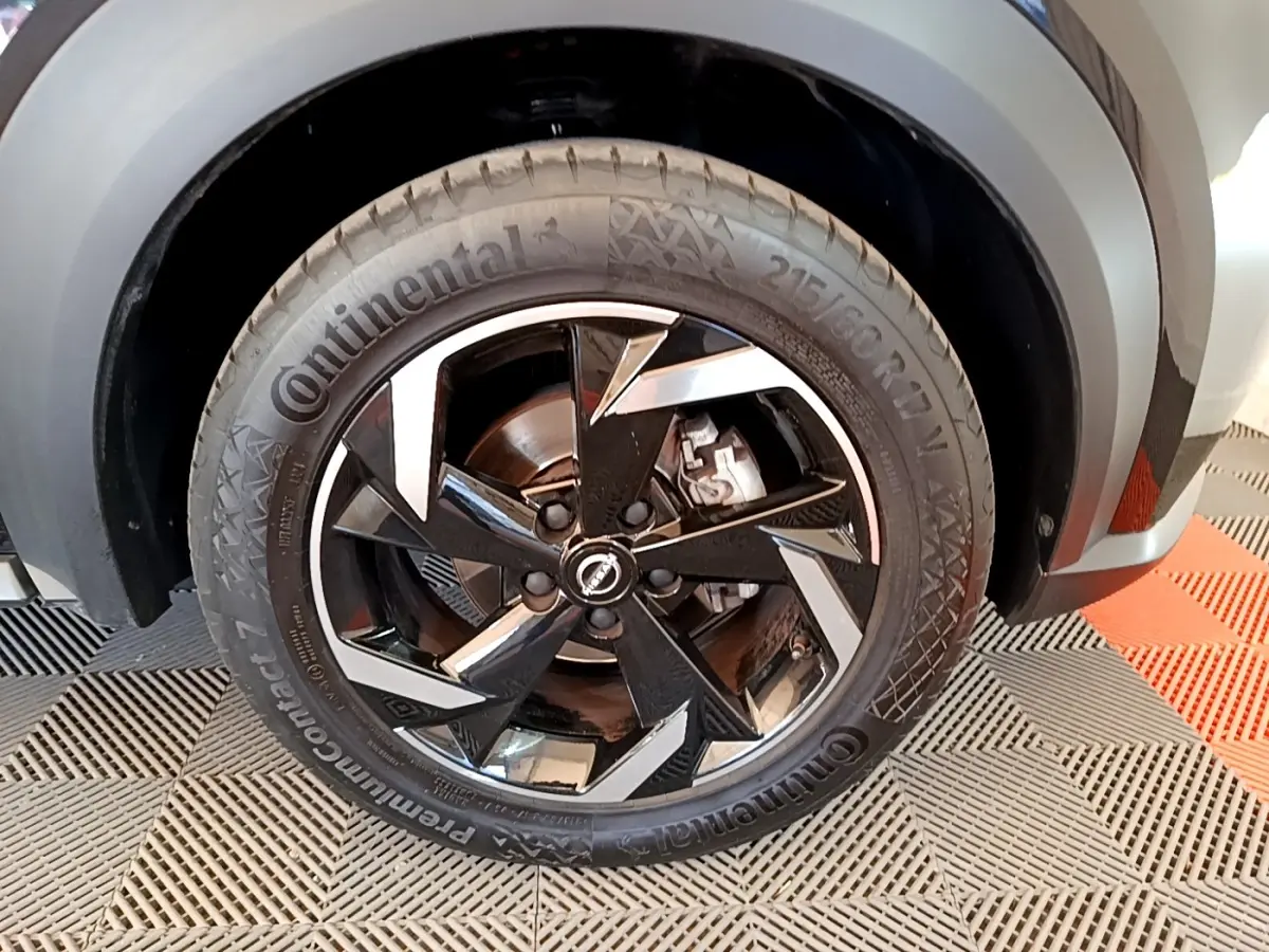 Gros plan sur la roue avant droite noire du Nissan Juke 2022 avec jante alliage au design géométrique.