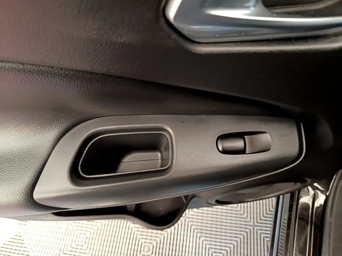 Poignée intérieure de porte côté conducteur en plastique noir sur Nissan Juke DIG-T 114 DCT noir, vue rapprochée.