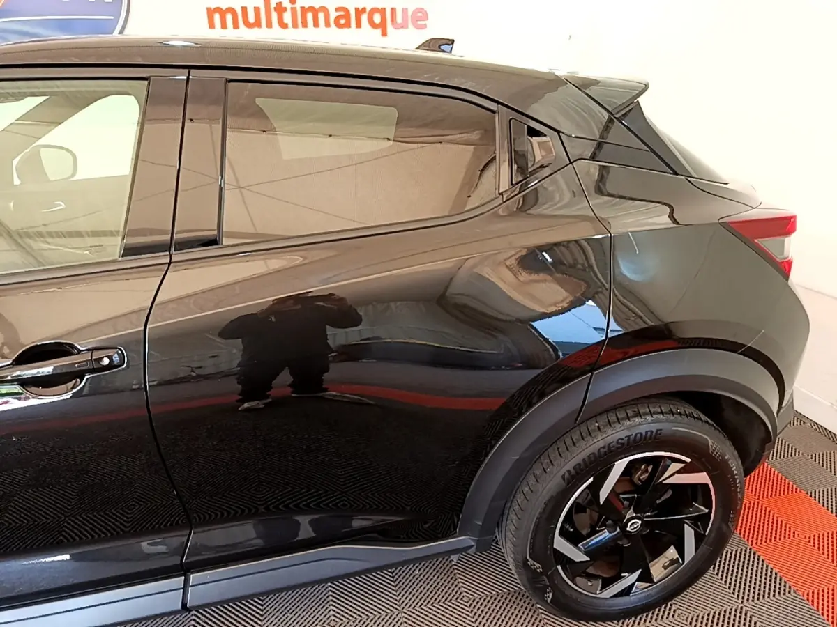 Vue latérale droite du Nissan Juke DIG-T 114 DCT noir 2022, mettant en valeur la porte arrière et la roue arrière au design moderne.