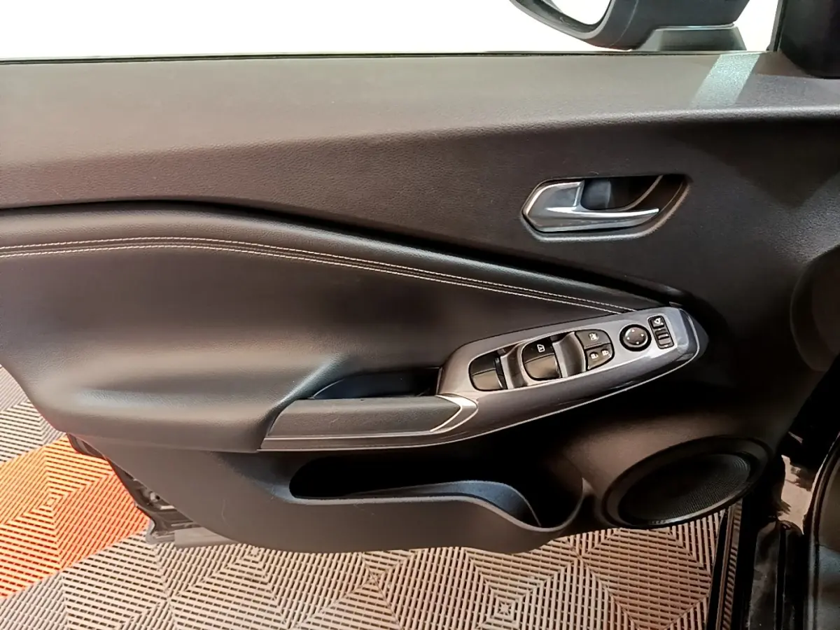 Vue rapprochée de la porte avant gauche noire du Nissan Juke 2022, avec commandes électriques et poignée argentée.