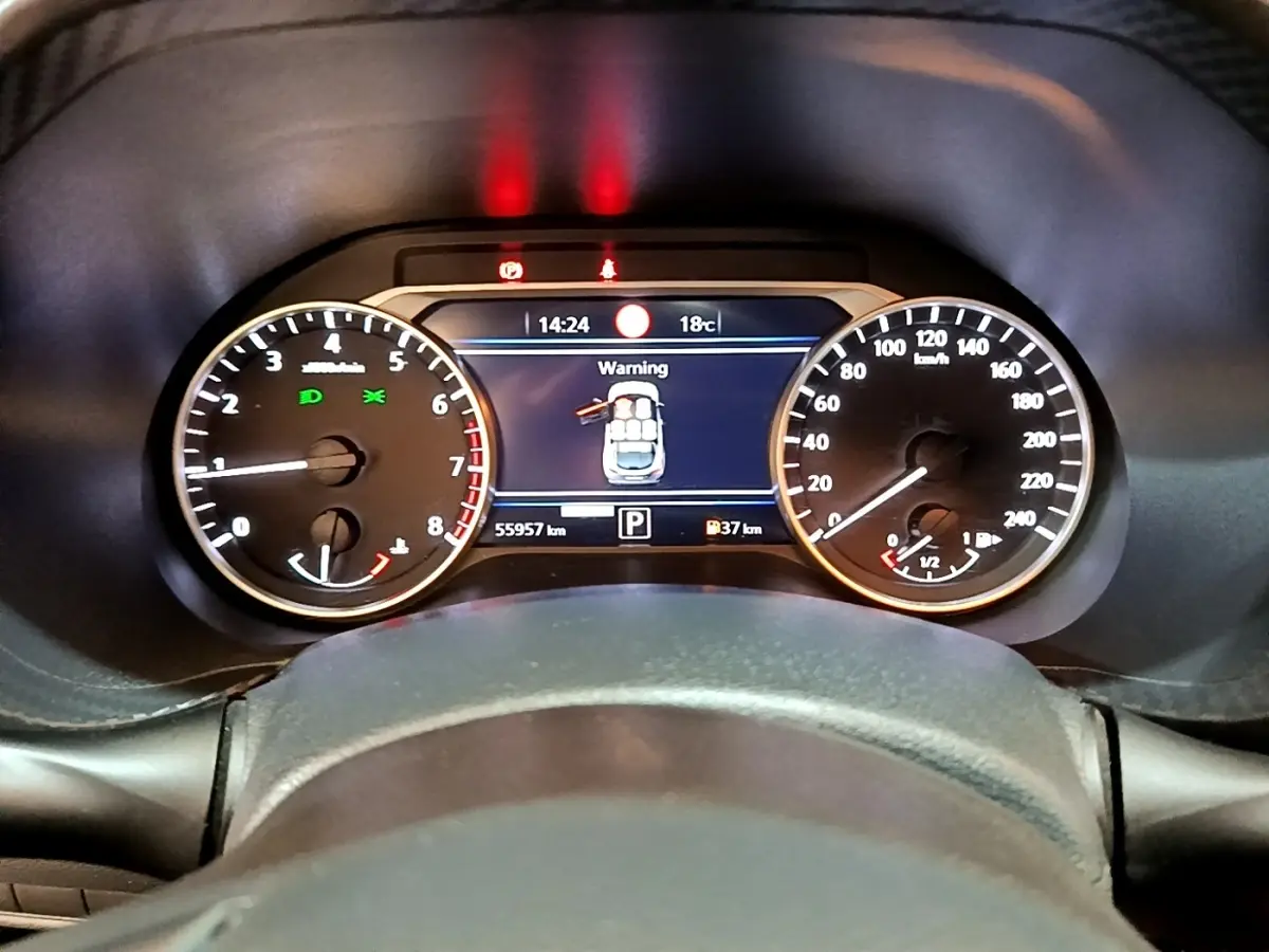 Vue rapprochée du tableau de bord numérique du Nissan Juke noir 2022, affichant une alerte de porte ouverte.