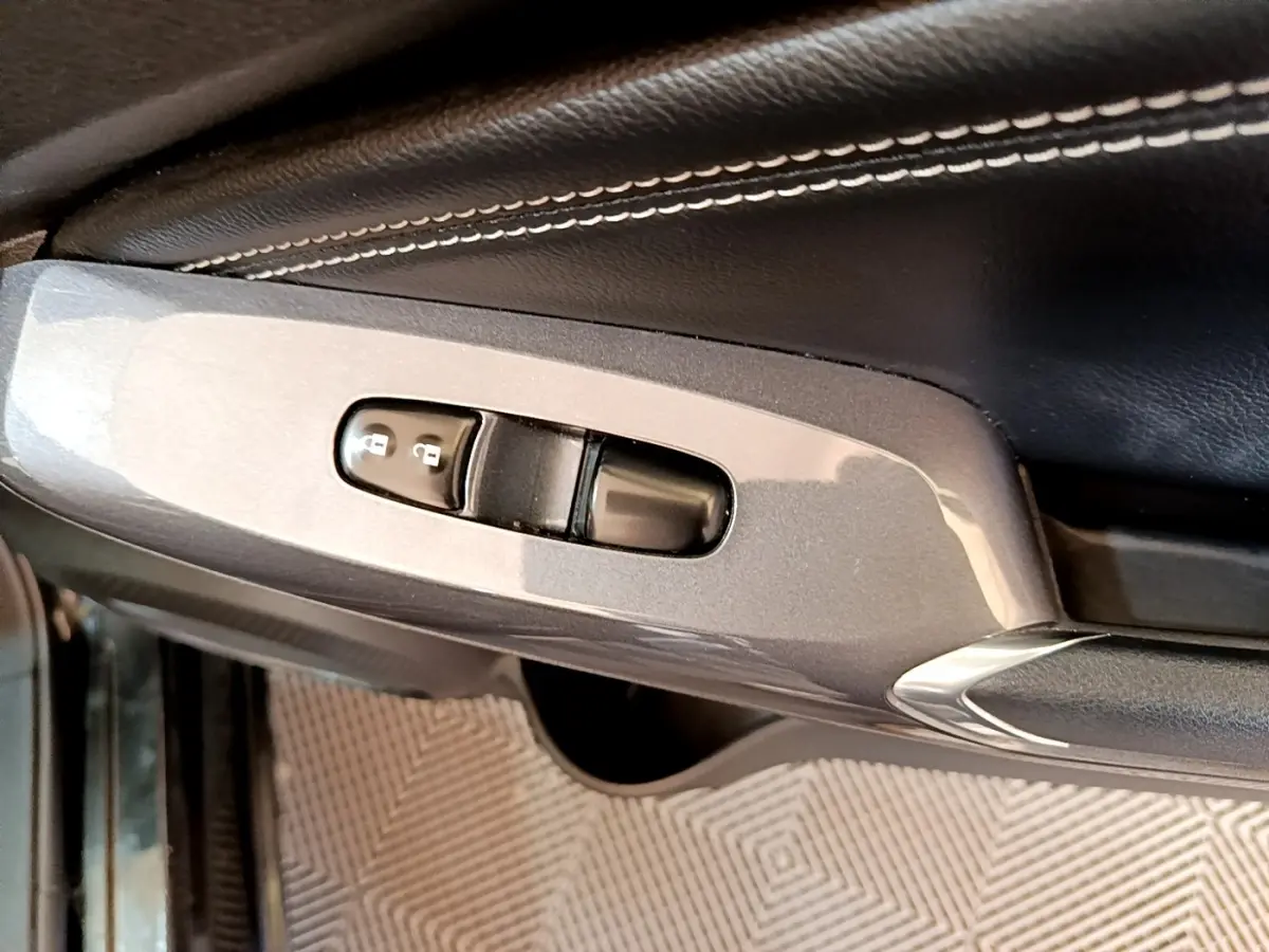 Gros plan sur la commande de verrouillage des portes sur la portière côté conducteur d’un Nissan Juke noir 2022.