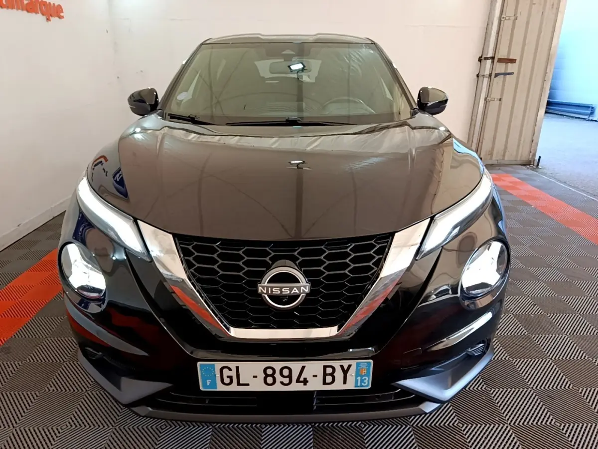 Vue avant d'un Nissan Juke noir 2022 avec calandre en V chromée et phares ronds LED allumés.