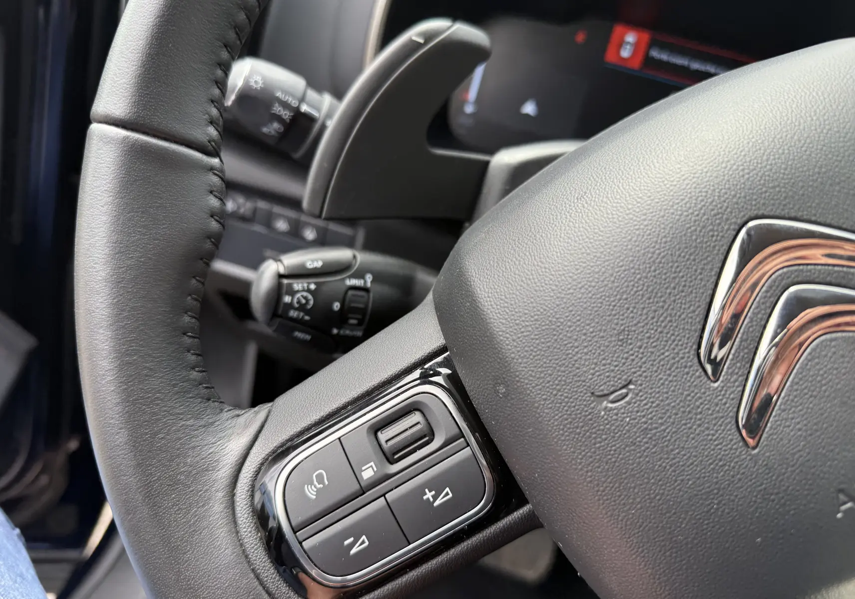 Gros plan sur le volant en cuir noir du Citroën C5 Aircross Hybrid 2025, montrant les commandes multifonctions côté gauche.