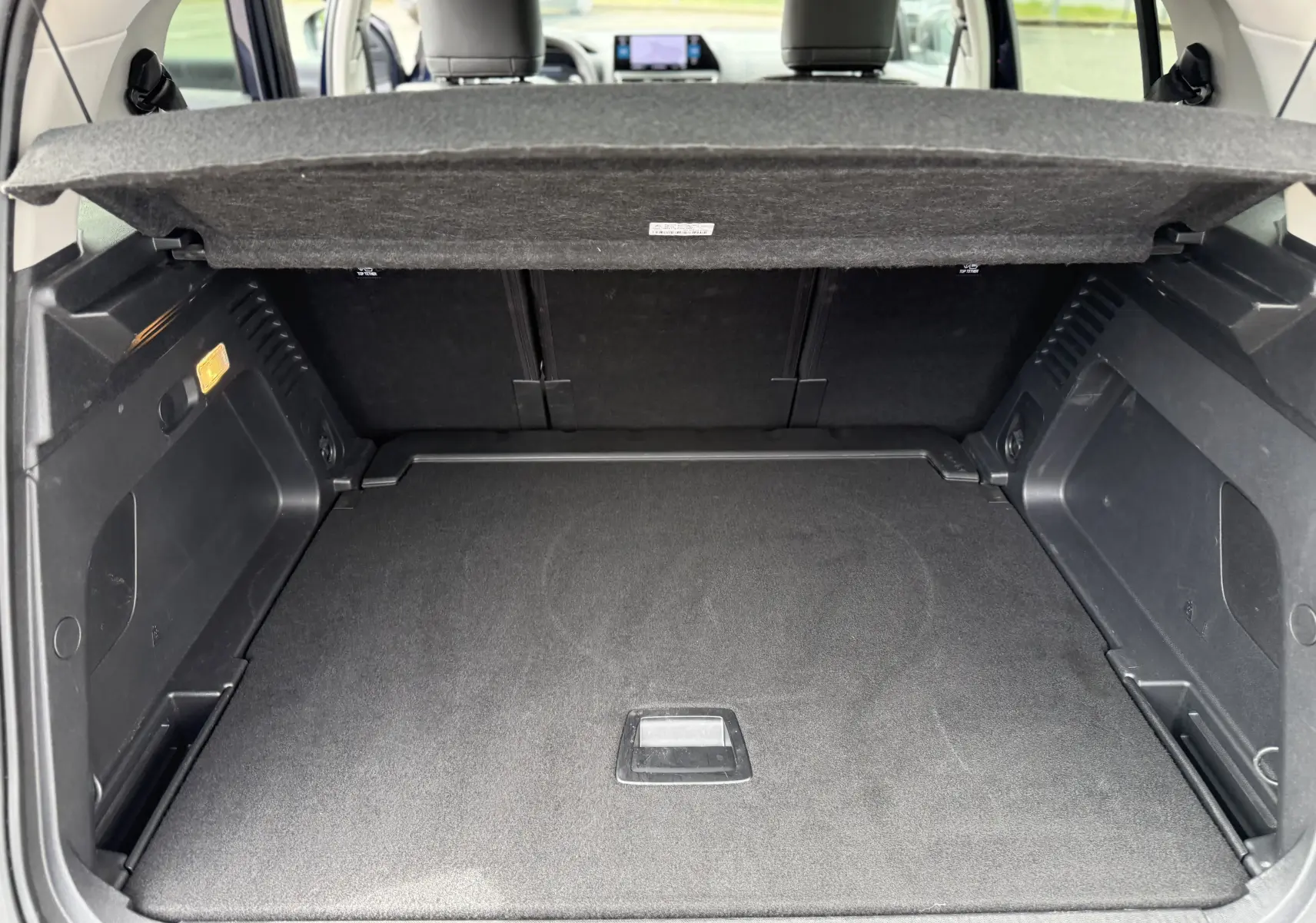 Coffre ouvert vu de l'arrière d'un Citroën C5 Aircross Hybrid 145 e-DSC6 Max, intérieur noir spacieux et propre.