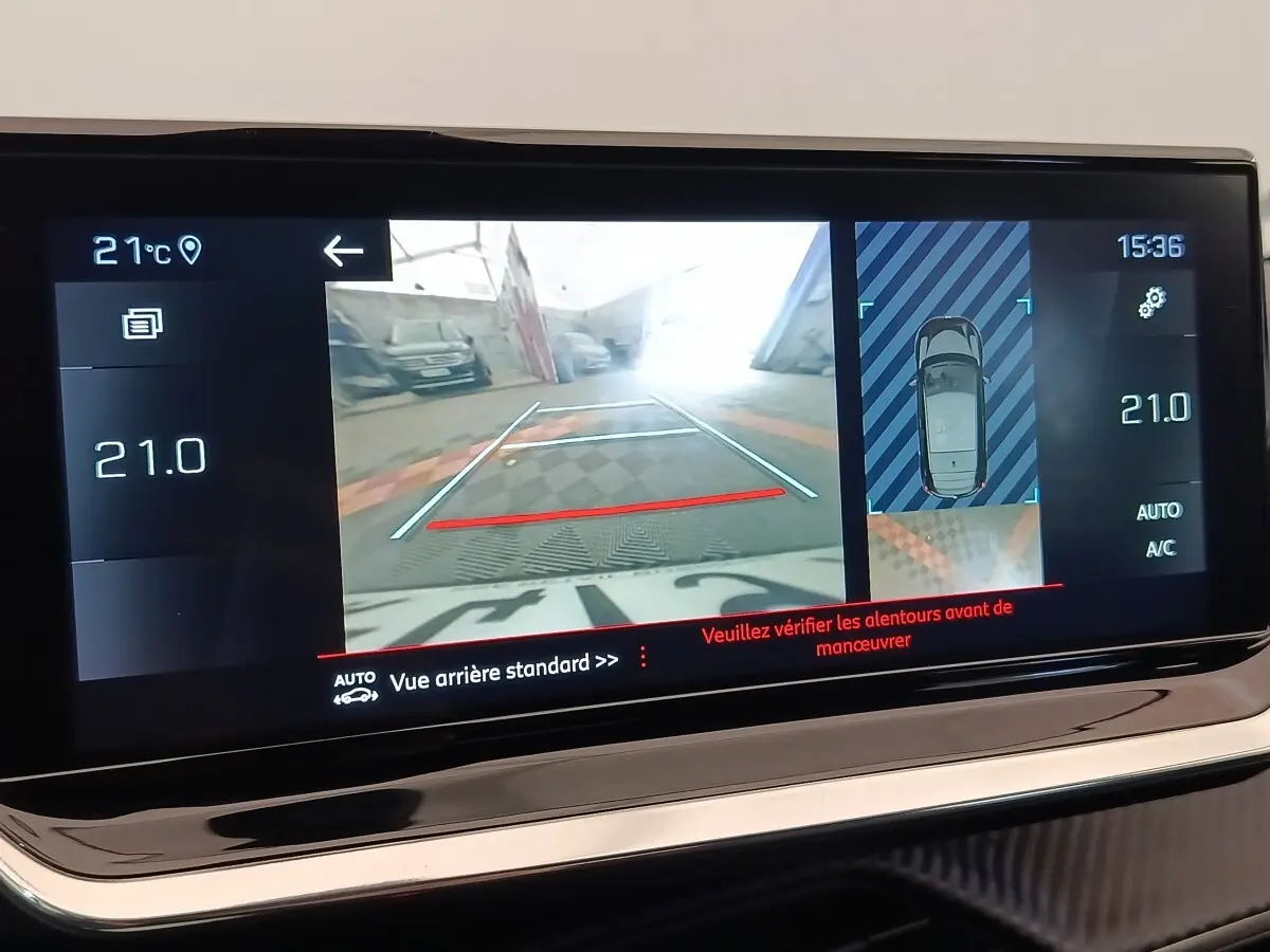 Écran tactile de la Peugeot 208 blanc montrant la caméra de recul et l’aide au stationnement arrière.