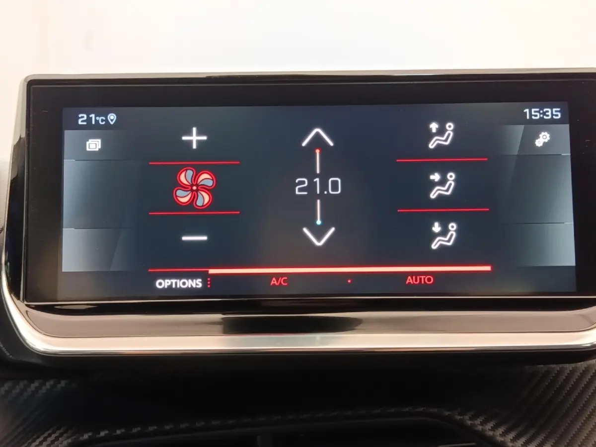 Écran tactile du tableau de bord de la Peugeot 208 blanc, affichant la climatisation à 21°C en mode automatique.