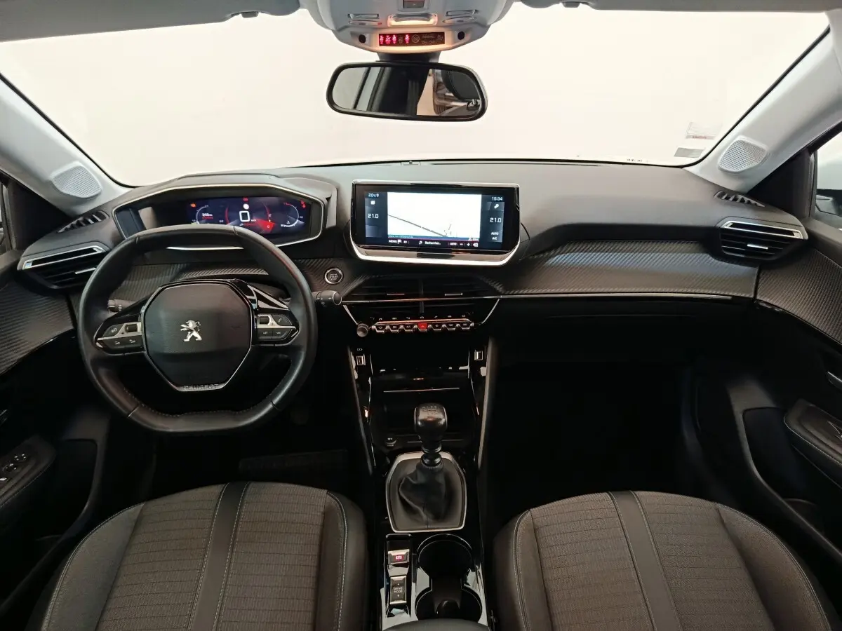 Vue intérieure frontale du tableau de bord noir et volant cuir de la Peugeot 208 PureTech 100 S&S Allure Business 2021.