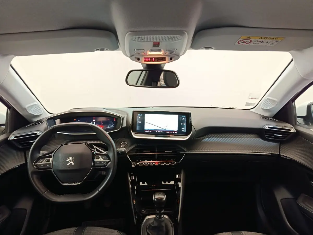 Vue intérieure avant du tableau de bord noir et volant cuir de la Peugeot 208 PureTech 100 S&S Allure Business 2021.
