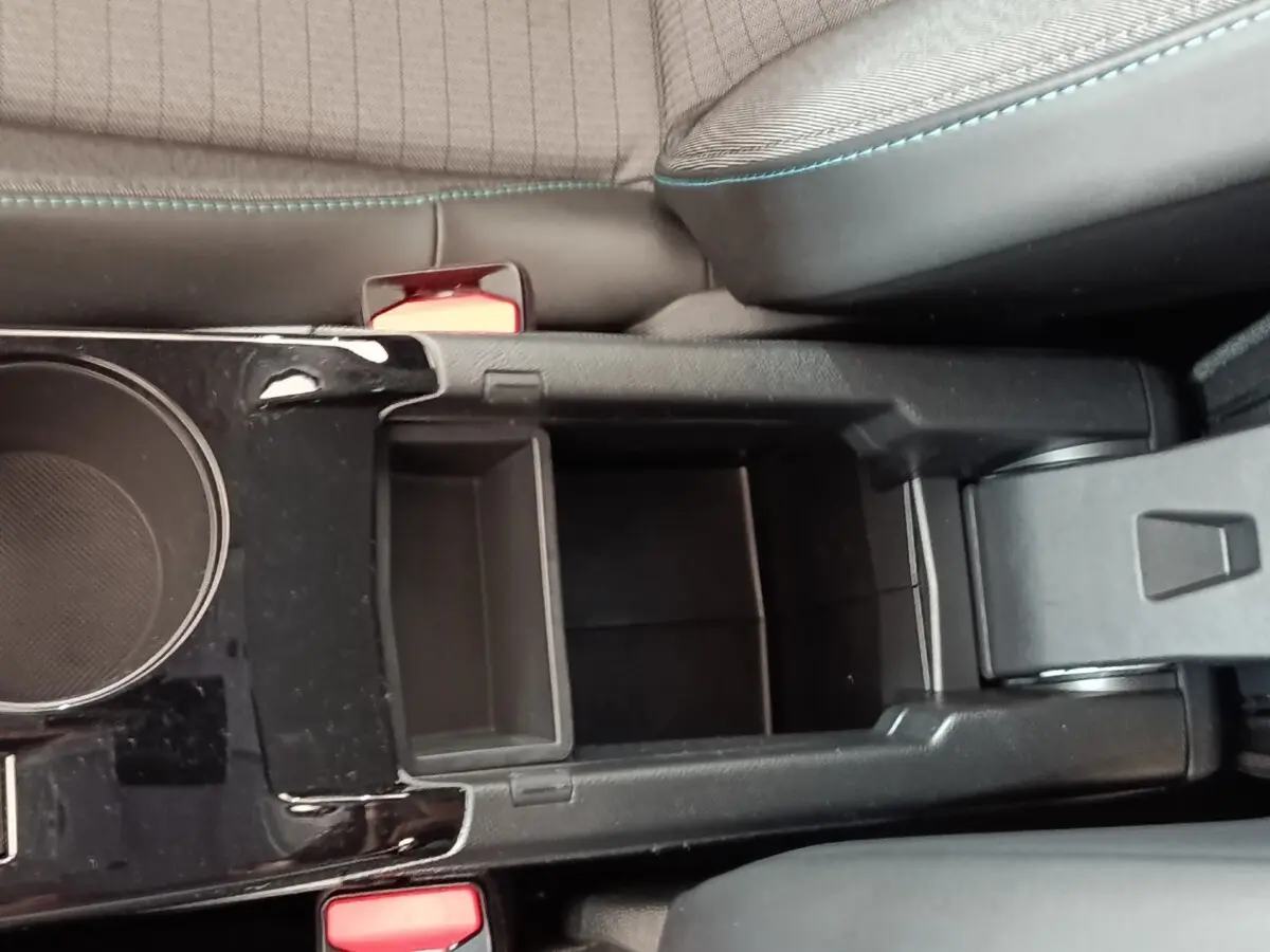 Vue plongeante sur la console centrale noire de la Peugeot 208 blanche, avec porte-gobelets et accoudoir ouvert.