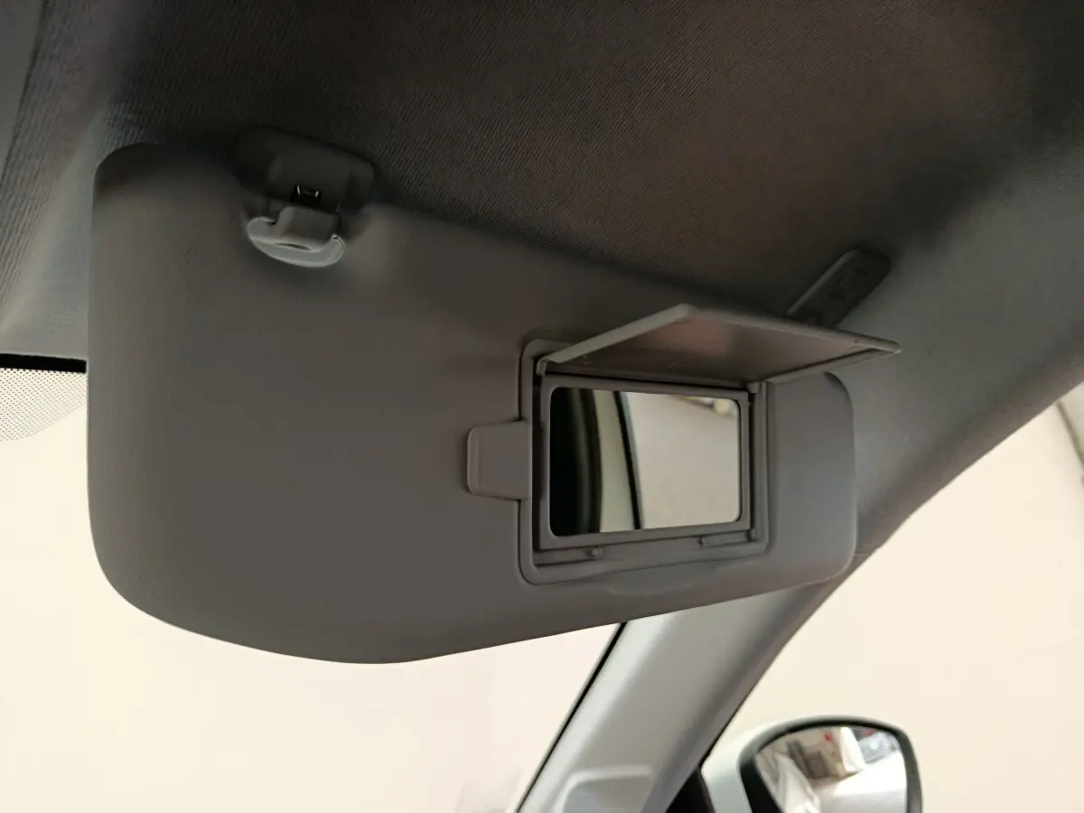 Détail intérieur du pare-soleil côté conducteur avec miroir de courtoisie ouvert dans une Peugeot 208 blanche.