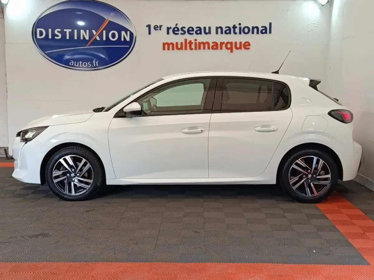 Profil droit d'une Peugeot 208 blanche PureTech 100 S&S Allure Business de 2021, avec jantes alliage et feux arrière LED.