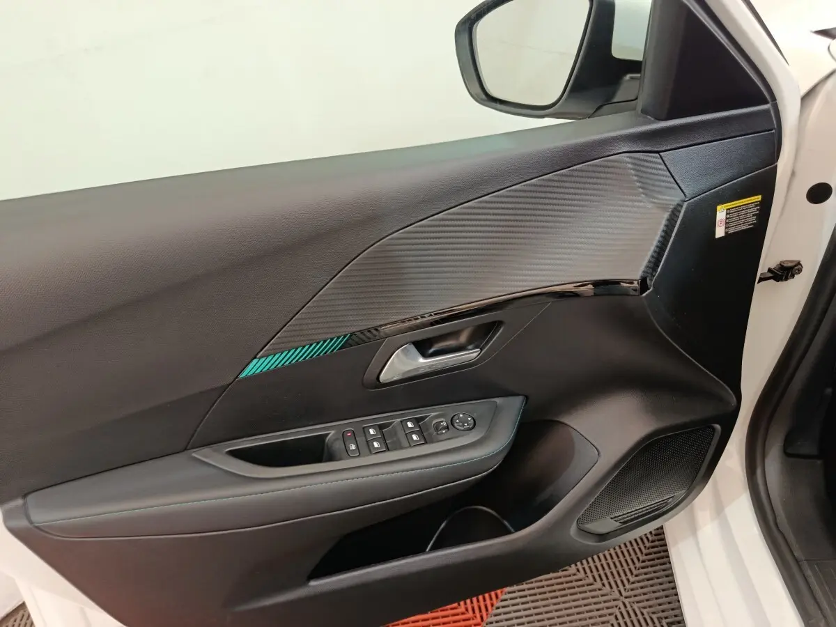 Intérieur de la porte avant gauche blanche d'une Peugeot 208 2021, avec insert décoratif et commandes électriques.