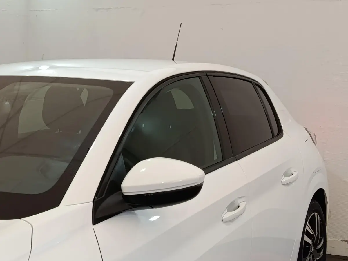 Vue latérale droite d'une Peugeot 208 blanche avec rétroviseur et poignées assortis, vitres teintées.