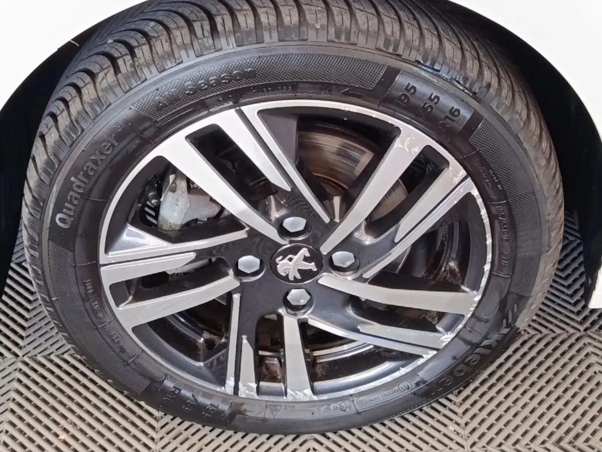 Gros plan sur la jante alliage bicolore et pneu noir du côté avant droit d’une Peugeot 208 blanche.