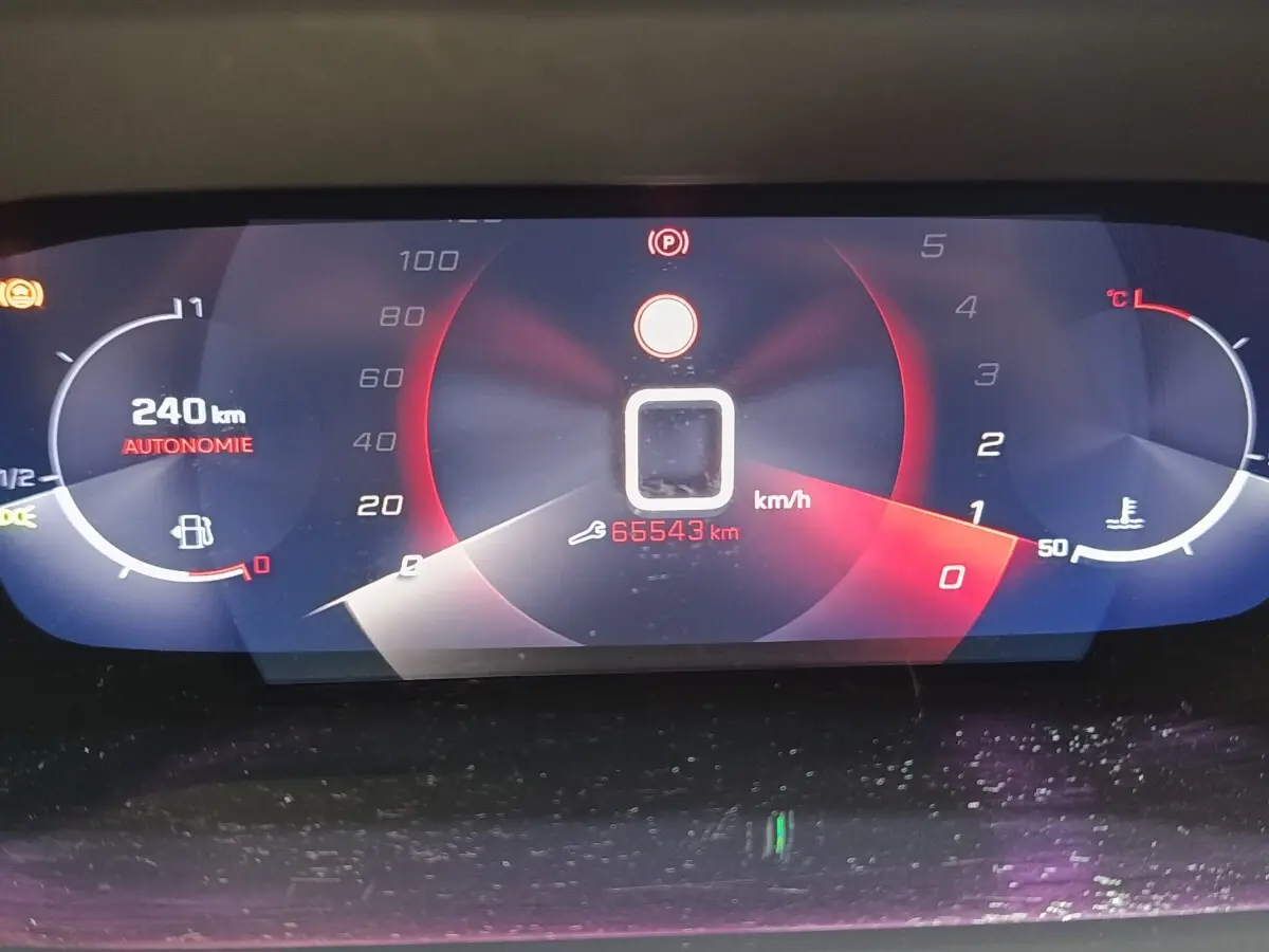 Affichage numérique du tableau de bord de la Peugeot 208 PureTech 100, montrant la vitesse, autonomie et température moteur.
