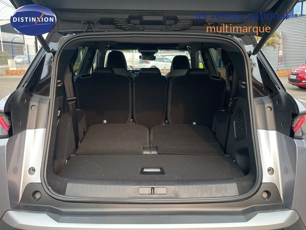 Coffre ouvert en vue arrière d'un Peugeot 5008 gris Artense métal avec toit noir, sièges arrière partiellement rabattus.