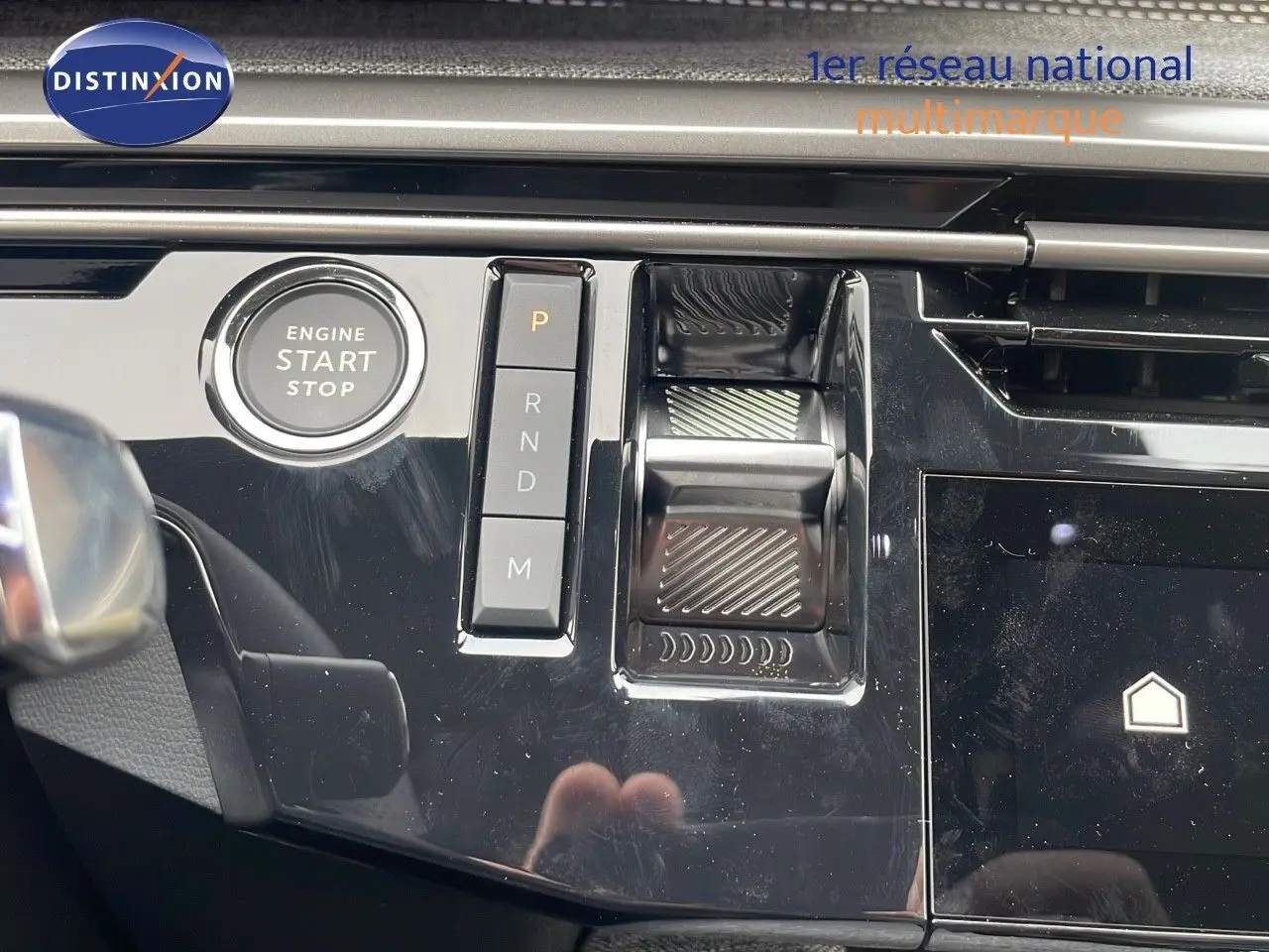 Gros plan sur la console centrale du Peugeot 5008 Hybrid 2025, avec bouton start/stop et commandes de boîte automatique.