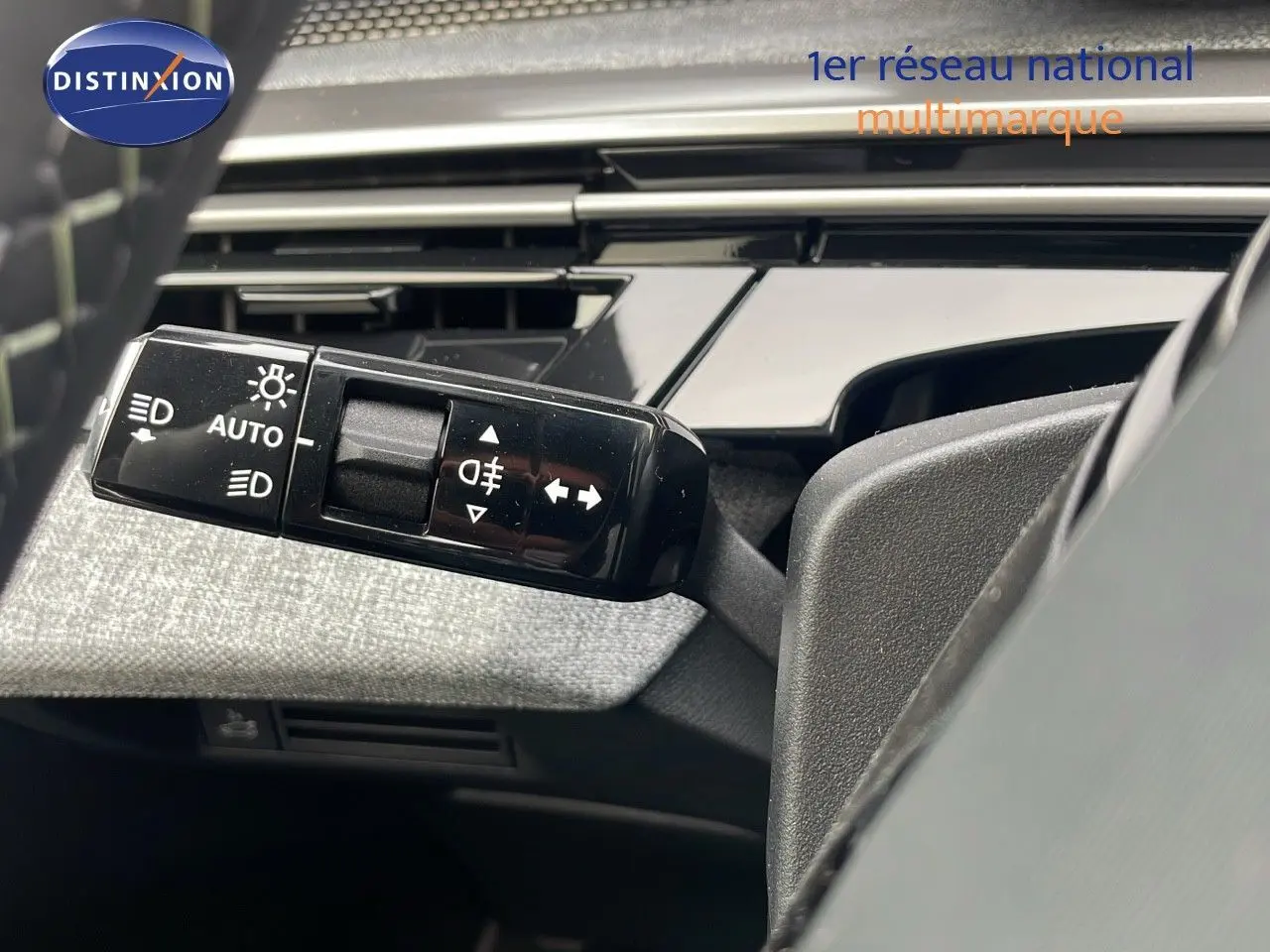 Gros plan sur la commande des feux et clignotants à gauche du volant dans un Peugeot 5008 gris Artense 2025.