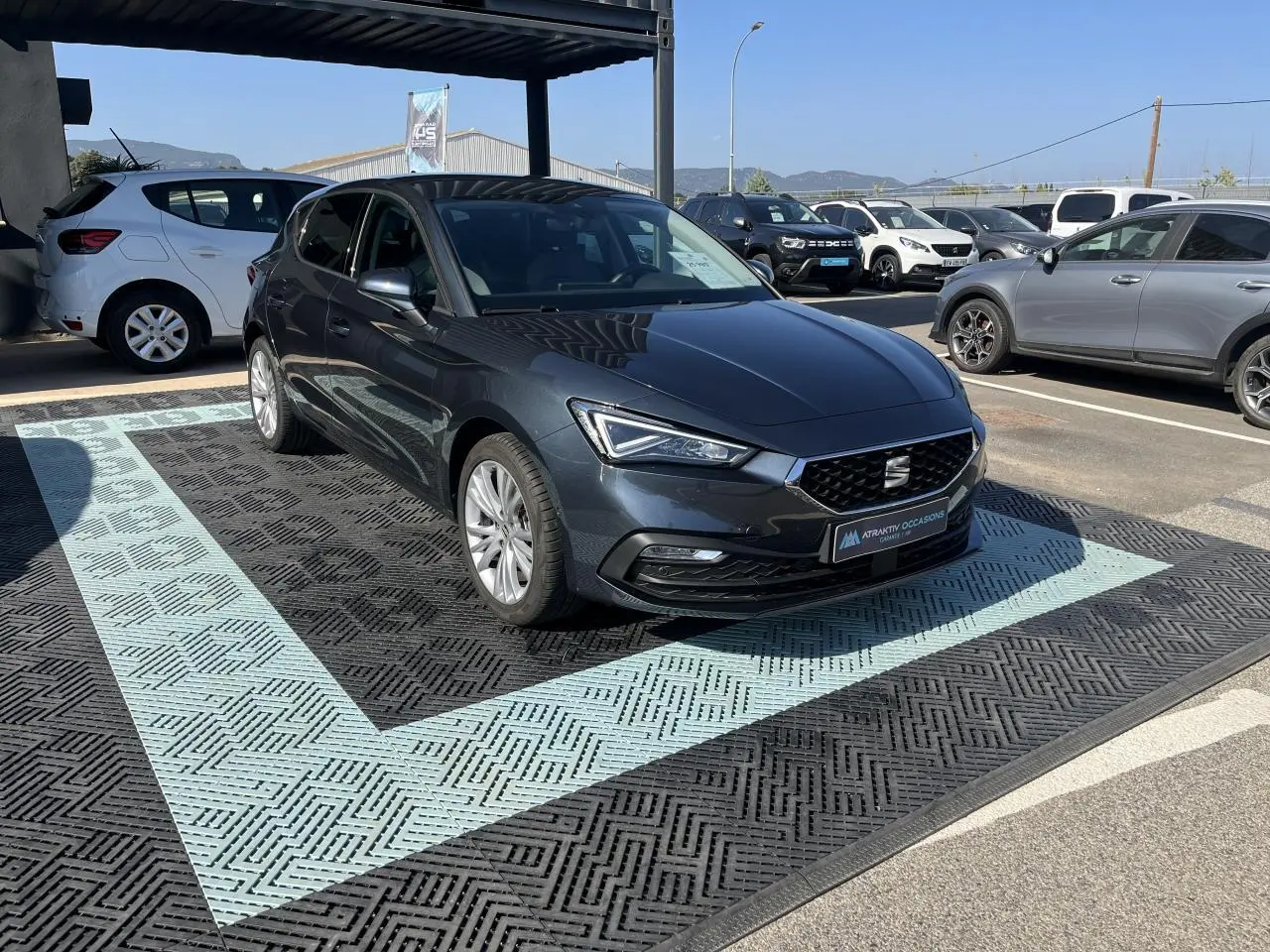 SEAT Leon IV gris Magnetic Metal vue 3/4 avant droit, avec jantes alliage 17 pouces et phares LED allumés.