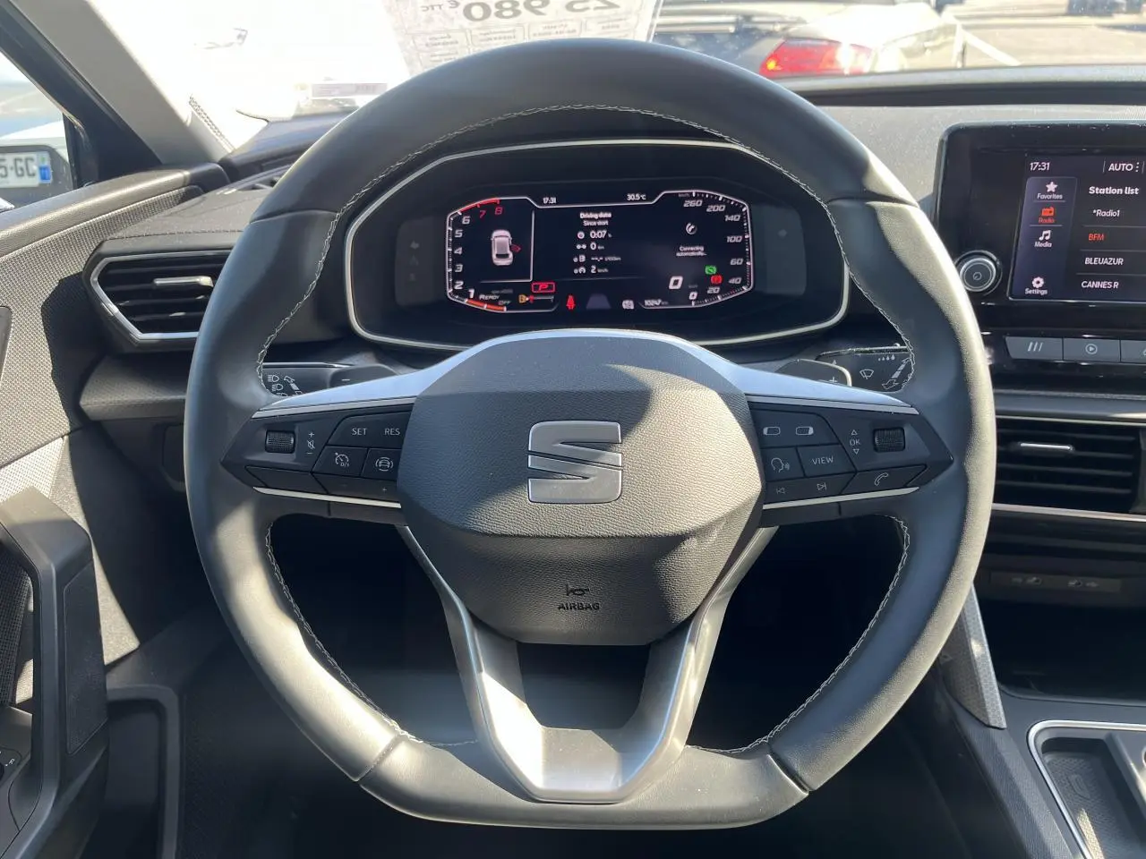 Volant cuir multifonction SEAT Leon IV 2023 vu de face, avec tableau de bord digital et écran central tactile.