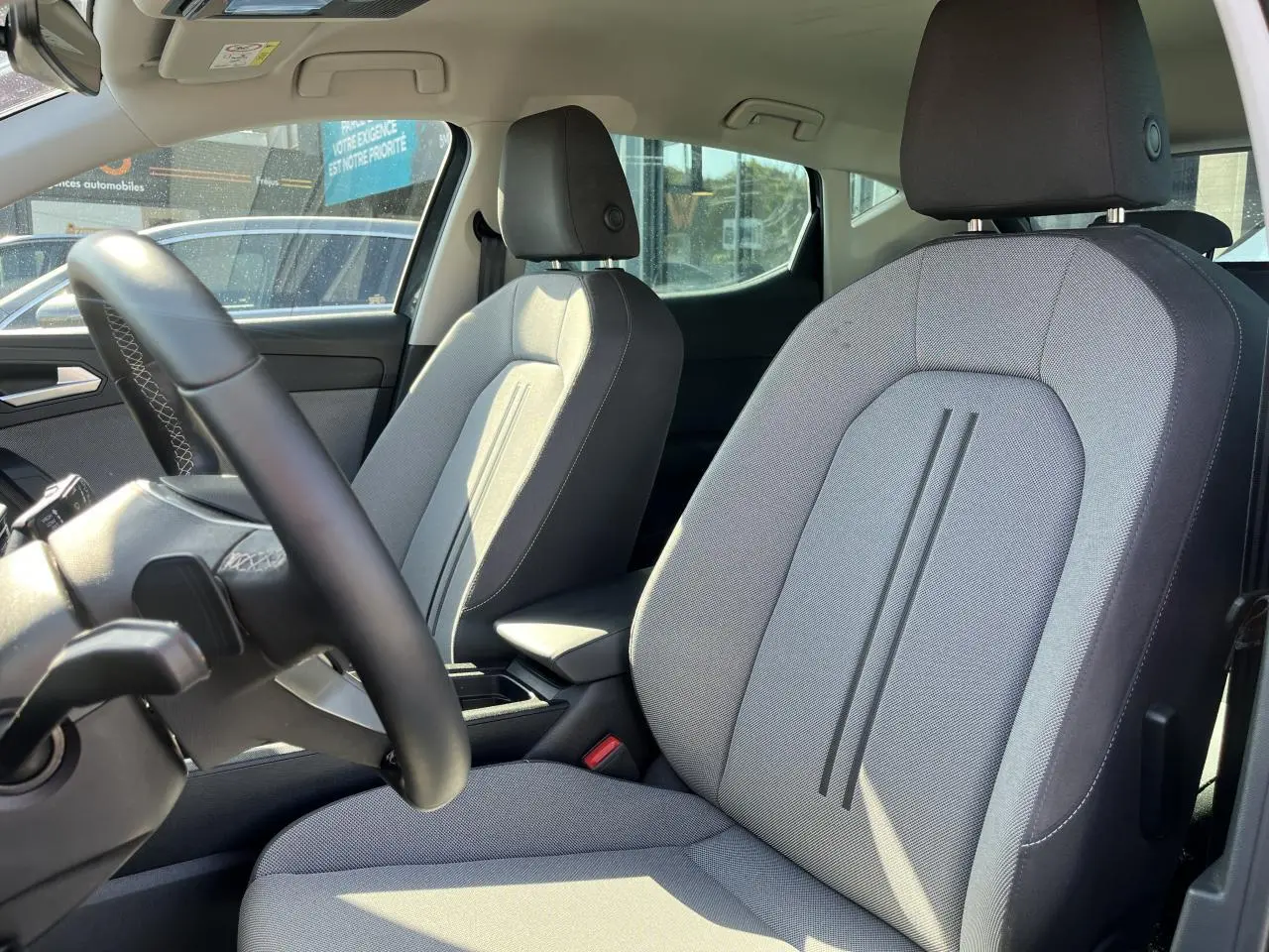 Vue intérieure sur les sièges avant gris clair et volant cuir multifonction du SEAT LEON IV 1.5 ETSI 150 SPECIALE EDITION 2023.