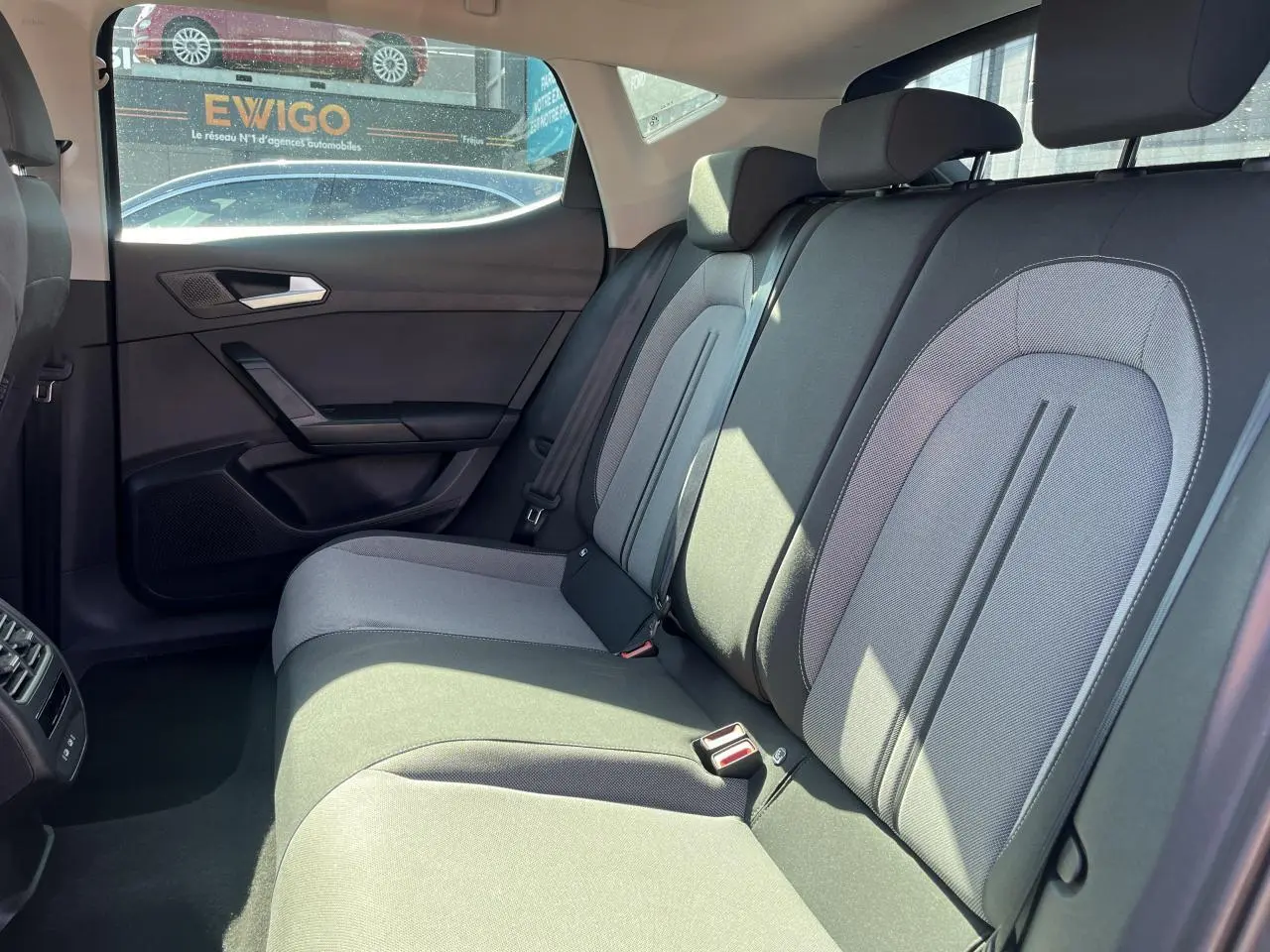 Vue intérieure sur la banquette arrière grise de la SEAT LEON IV 2023, avec appuie-têtes et ceintures visibles.